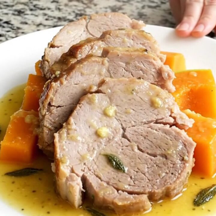 A succulent slow cooker pork loin served with tender butternut squash on a white plate.