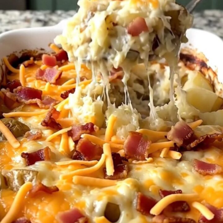 A top-down view of a rectangular baking dish filled with cubes of twice baked potatoes topped with cheese and bacon.