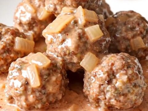 A slow cooker filled with turkey meatballs covered in a thick, creamy pink vodka sauce.