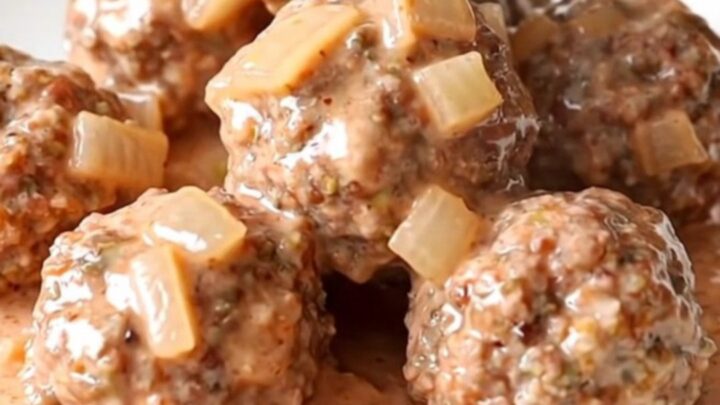 A slow cooker filled with turkey meatballs covered in a thick, creamy pink vodka sauce.