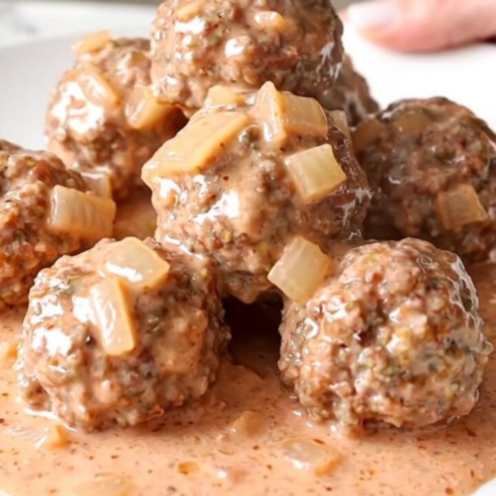 A slow cooker filled with turkey meatballs covered in a thick, creamy pink vodka sauce.