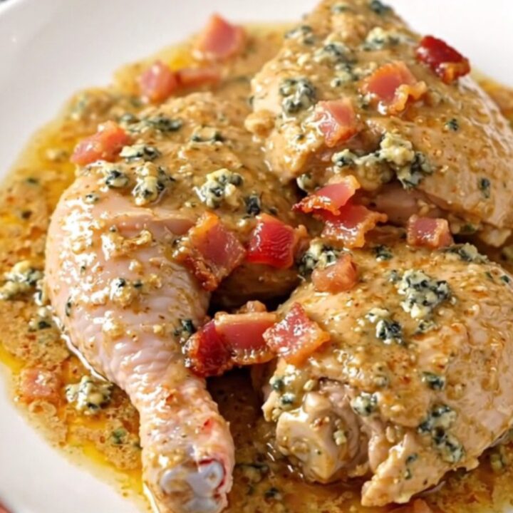 A slow cooker filled with chicken thighs, bacon, and blue cheese ready for cooking.