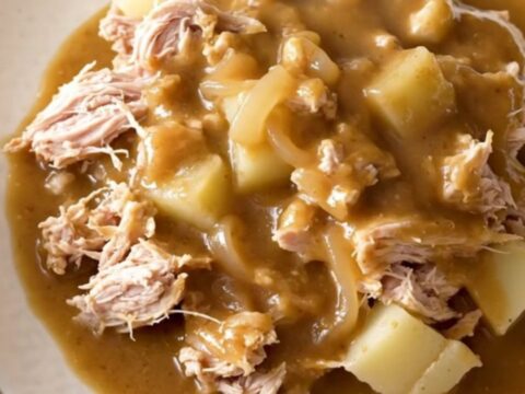 A close-up of a slow cooker filled with ground turkey, potatoes, and savory onion gravy.