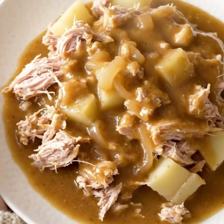 A close-up of a slow cooker filled with ground turkey, potatoes, and savory onion gravy.
