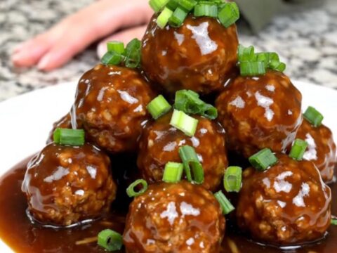 A close-up of tender turkey meatballs glazed in a dark, glossy Mongolian sauce inside a slow cooker.