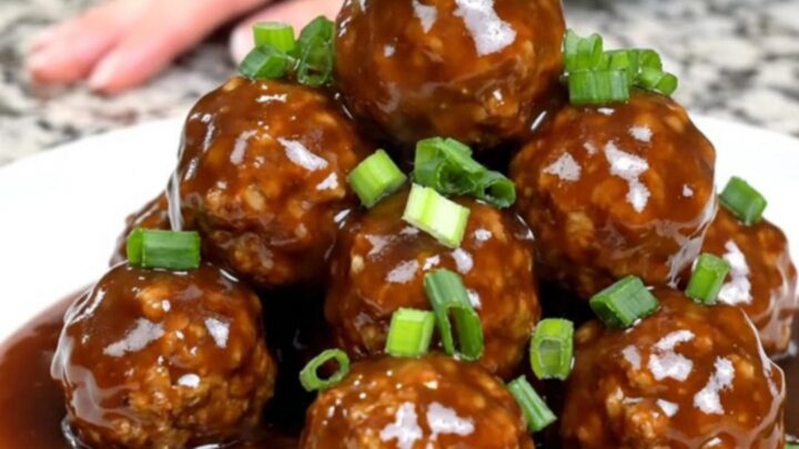 A close-up of tender turkey meatballs glazed in a dark, glossy Mongolian sauce inside a slow cooker.