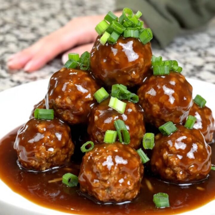 A close-up of tender turkey meatballs glazed in a dark, glossy Mongolian sauce inside a slow cooker.
