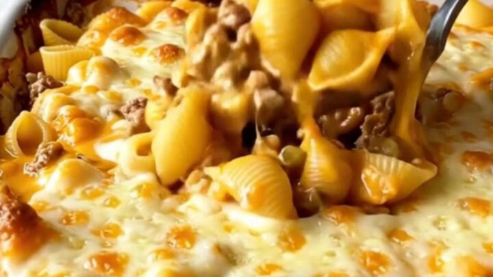 A top-down view of a cheeseburger shells bake in a white ceramic dish with melted cheddar.