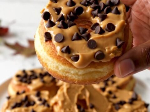 A close-up of fresh red apple rings topped with creamy peanut butter and scattered mini chocolate chips.