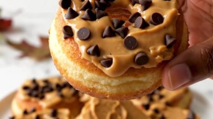 A close-up of fresh red apple rings topped with creamy peanut butter and scattered mini chocolate chips.