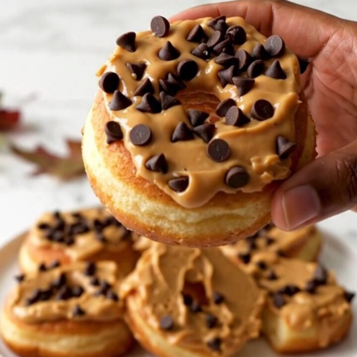 A close-up of fresh red apple rings topped with creamy peanut butter and scattered mini chocolate chips.