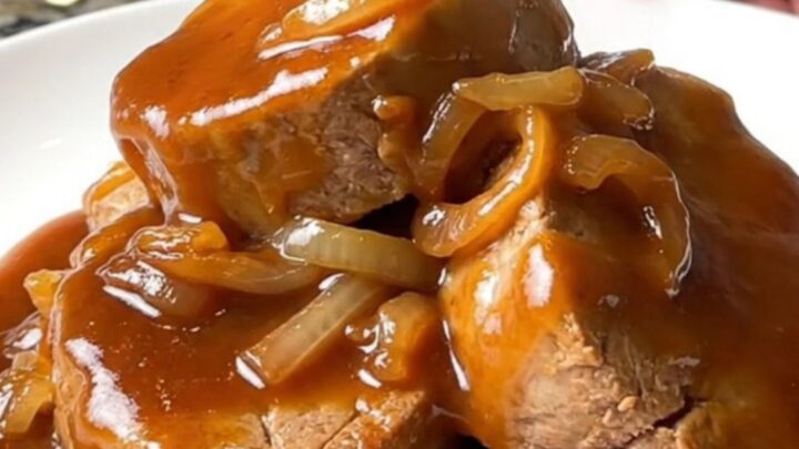 Succulent honey BBQ pork tenderloin medallions glazed in a thick, shiny sauce on a white plate.