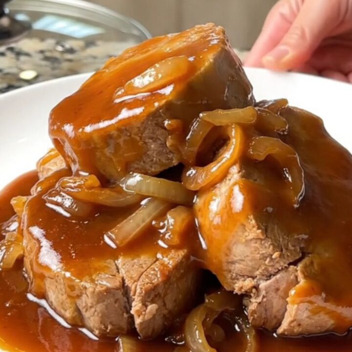 Succulent honey BBQ pork tenderloin medallions glazed in a thick, shiny sauce on a white plate.