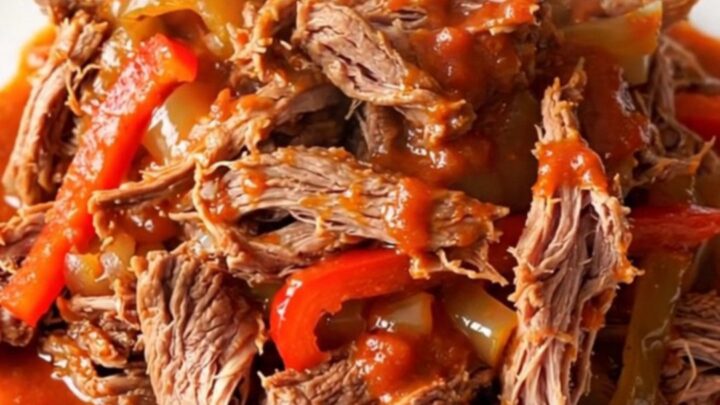 A close-up of tender, shredded beef Ropa Vieja in a rich tomato sauce with bell peppers.
