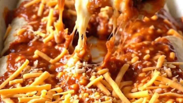 A top-down view of a rectangular baking dish filled with beef and bean burritos covered in red sauce and melted cheddar