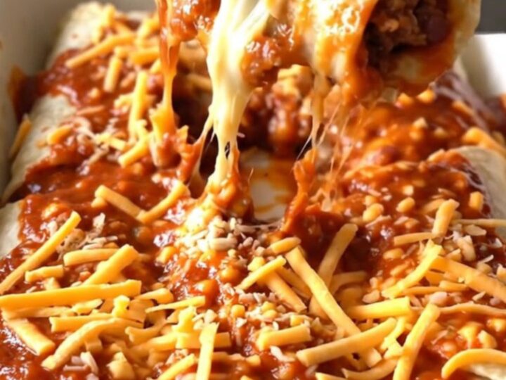 A top-down view of a rectangular baking dish filled with beef and bean burritos covered in red sauce and melted cheddar