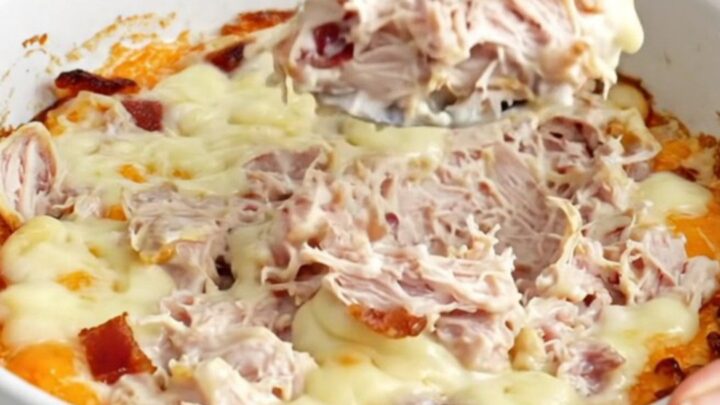 A top-down view of a slow cooker filled with creamy turkey and bacon dip, featuring melted cheese and visible chunks of meat.
