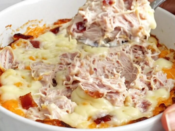 A top-down view of a slow cooker filled with creamy turkey and bacon dip, featuring melted cheese and visible chunks of meat.