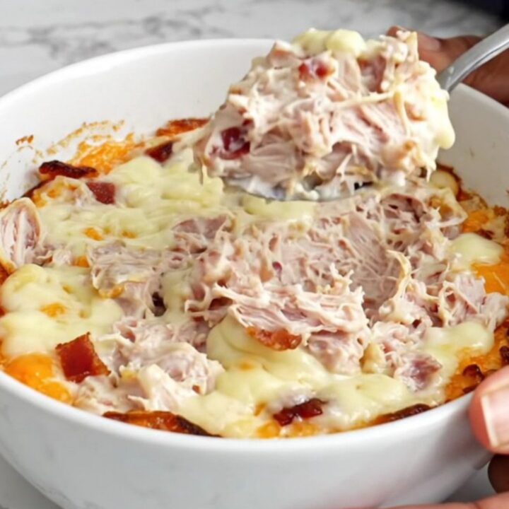 A top-down view of a slow cooker filled with creamy turkey and bacon dip, featuring melted cheese and visible chunks of meat.