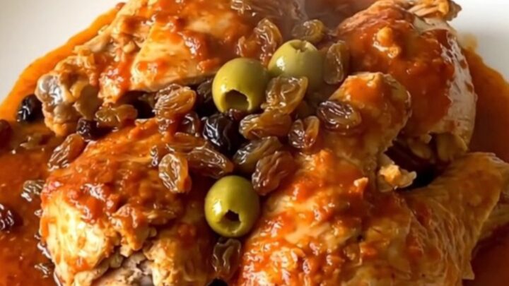 A close-up of slow cooker chicken picadillo in a serving bowl with visible chicken, potatoes, and olives.