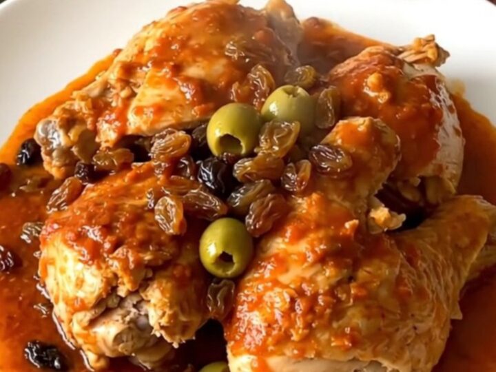 A close-up of slow cooker chicken picadillo in a serving bowl with visible chicken, potatoes, and olives.