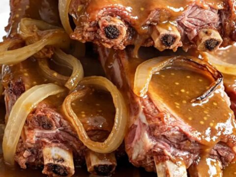 Slow cooker brown sugar Dijon baby back ribs served on a white plate with a glossy sauce.