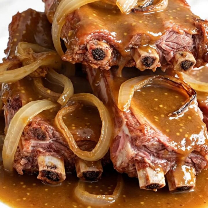 Slow cooker brown sugar Dijon baby back ribs served on a white plate with a glossy sauce.