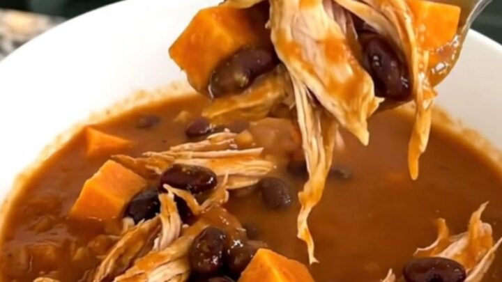 A bowl of hearty sweet potato chicken chili with visible chunks of potato and shredded chicken.