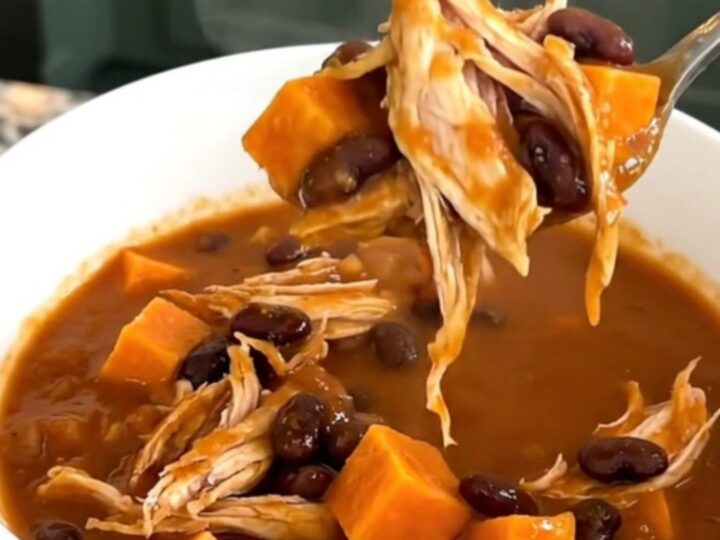 A bowl of hearty sweet potato chicken chili with visible chunks of potato and shredded chicken.