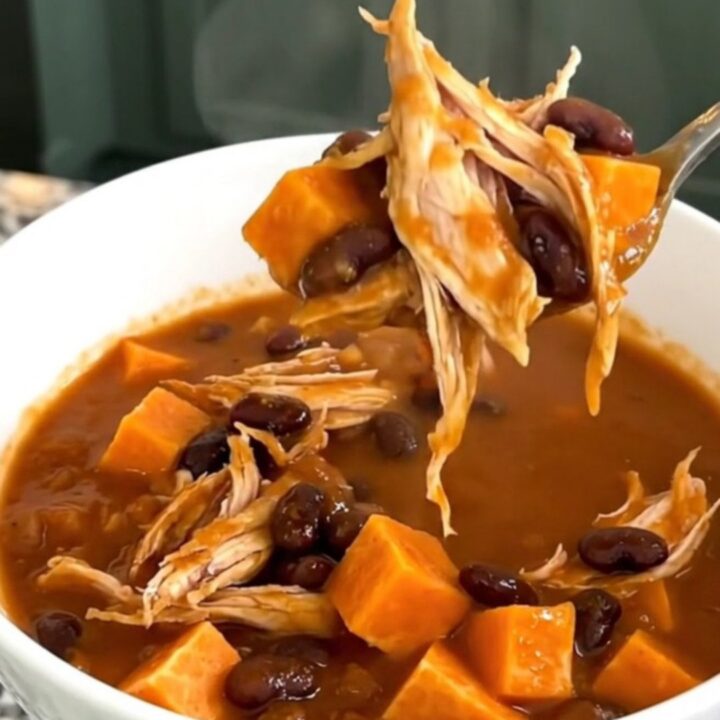 A bowl of hearty sweet potato chicken chili with visible chunks of potato and shredded chicken.