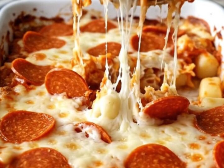 A top-down view of a rectangular white baking dish filled with potato gnocchi, pizza sauce, mozzarella, and pepperoni.