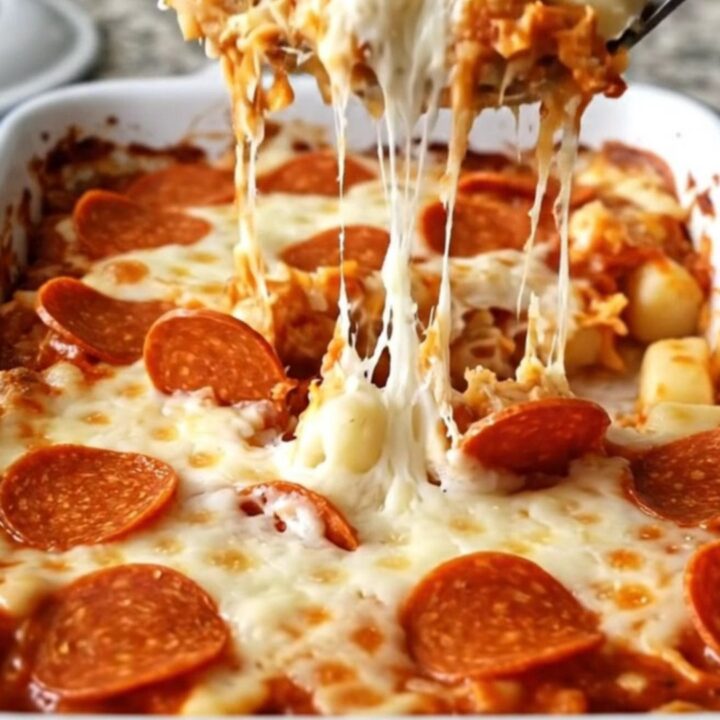 A top-down view of a rectangular white baking dish filled with potato gnocchi, pizza sauce, mozzarella, and pepperoni.