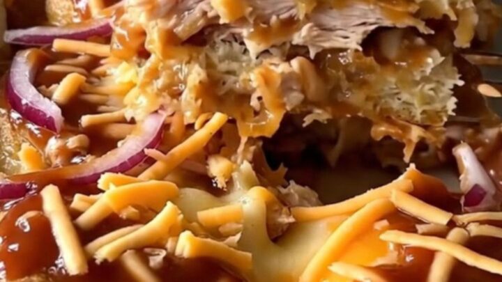 A top-down view of a rectangular baking dish filled with golden biscuits, shredded chicken, and barbecue sauce.