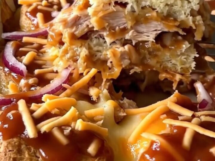 A top-down view of a rectangular baking dish filled with golden biscuits, shredded chicken, and barbecue sauce.