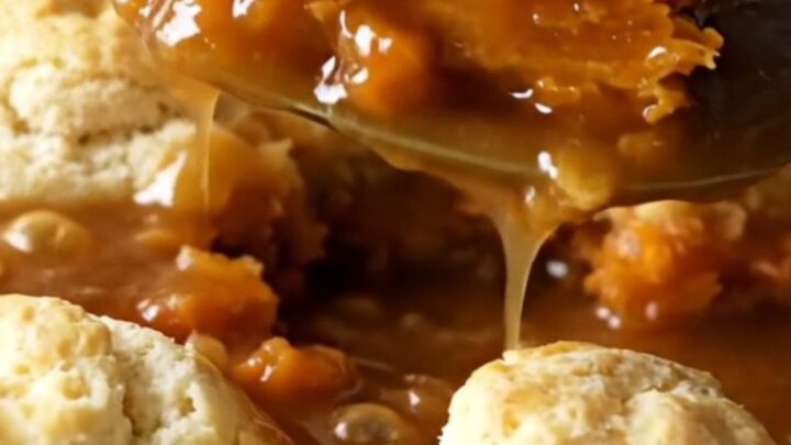 A top-down view of a rectangular baking dish filled with rows of sweet potato rounds topped with pieces of biscuit dough.