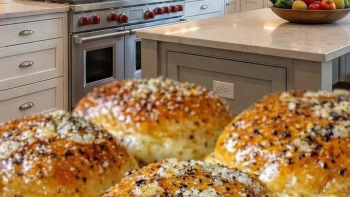 Four golden-brown garlic parmesan cheeseburger bombs arranged on a baking sheet.