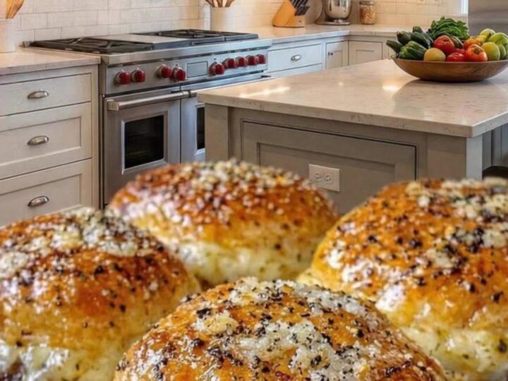 Four golden-brown garlic parmesan cheeseburger bombs arranged on a baking sheet.