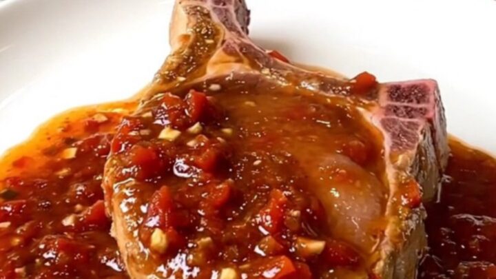 A serving spoon lifts a tender, saucy boneless pork chop from a slow cooker filled with chunky salsa.