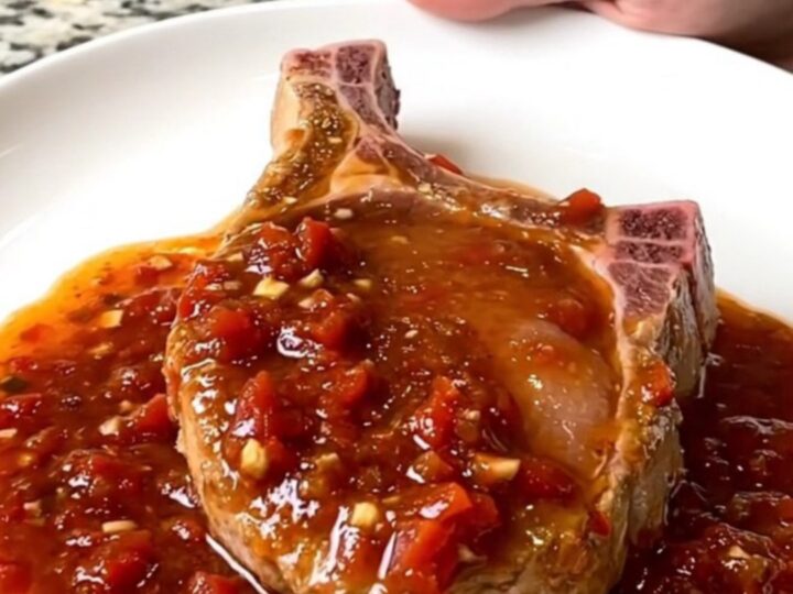 A serving spoon lifts a tender, saucy boneless pork chop from a slow cooker filled with chunky salsa.