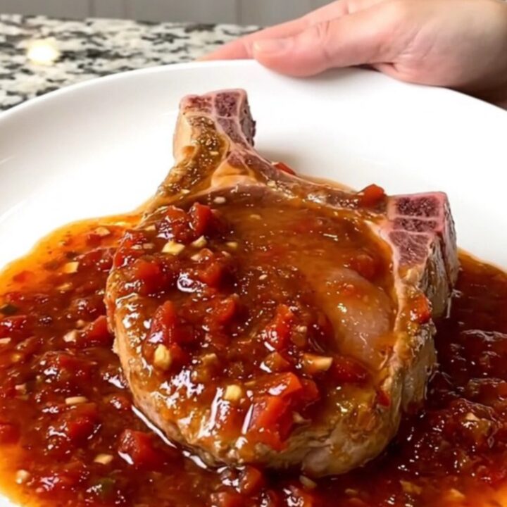 A serving spoon lifts a tender, saucy boneless pork chop from a slow cooker filled with chunky salsa.