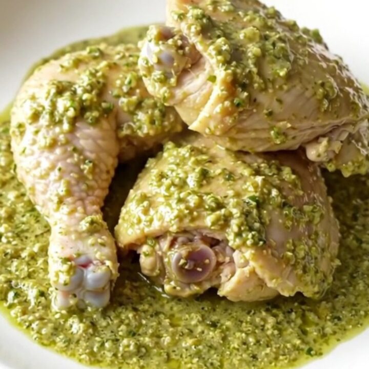 A close-up of tender chicken thighs covered in a creamy, vibrant green salsa verde sauce in a black slow cooker.