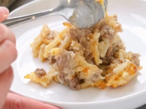A warm, creamy Amish beef and hashbrown casserole in a glass dish with steam rising.