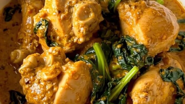 A close-up view of creamy chicken saag in a slow cooker, showing tender chicken pieces coated in a rich