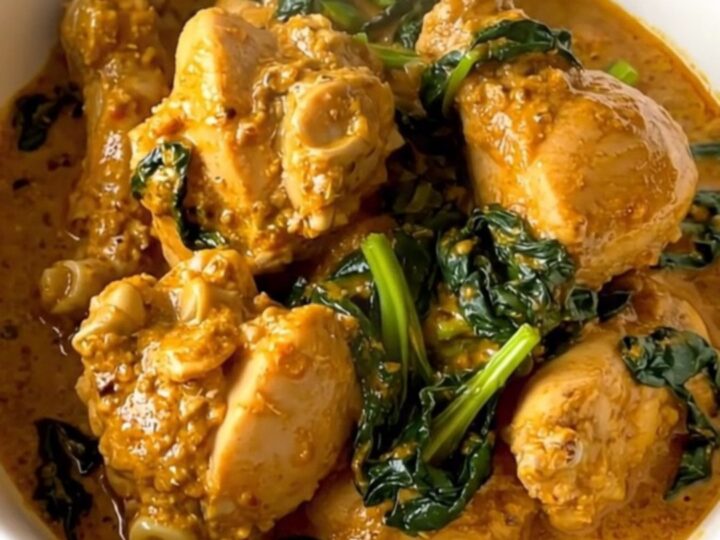 A close-up view of creamy chicken saag in a slow cooker, showing tender chicken pieces coated in a rich