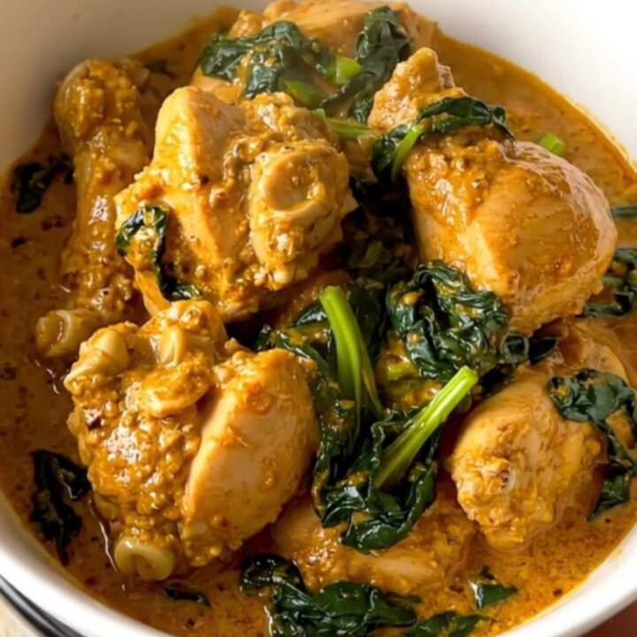 A close-up view of creamy chicken saag in a slow cooker, showing tender chicken pieces coated in a rich
