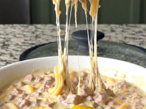 A warm, creamy Italian sub dip in a black slow cooker, topped with melted provolone and peppers.