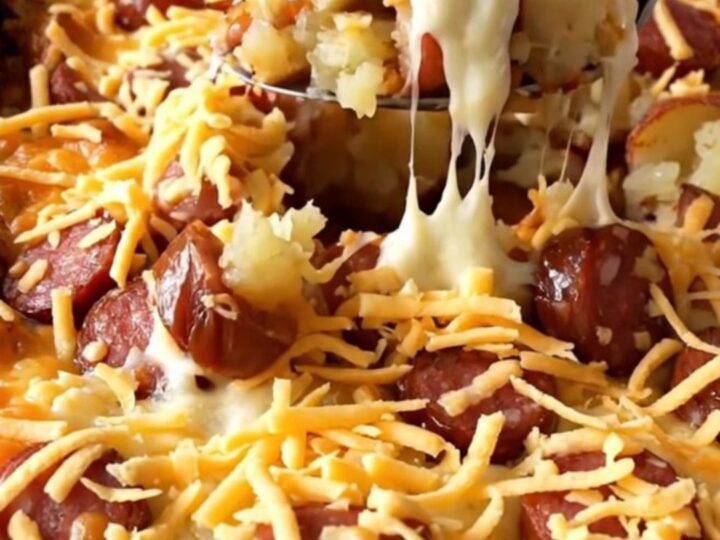A top-down view of a rectangular baking dish filled with raw diced red potatoes and sliced andouille sausage