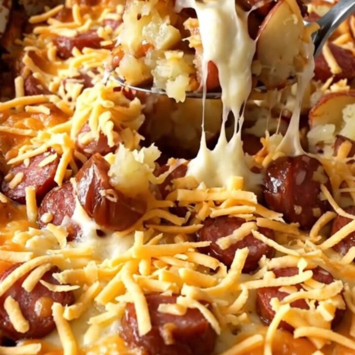 A top-down view of a rectangular baking dish filled with raw diced red potatoes and sliced andouille sausage