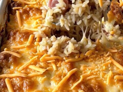 A top-down view of a rectangular baking dish filled with raw sausage crumbles and long-grain rice ready for the oven.
