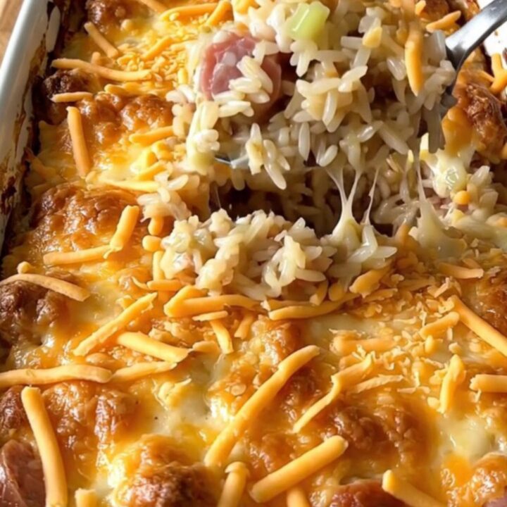 A top-down view of a rectangular baking dish filled with raw sausage crumbles and long-grain rice ready for the oven.